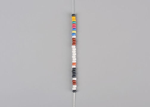 Column of multicolored seed beads on white thread